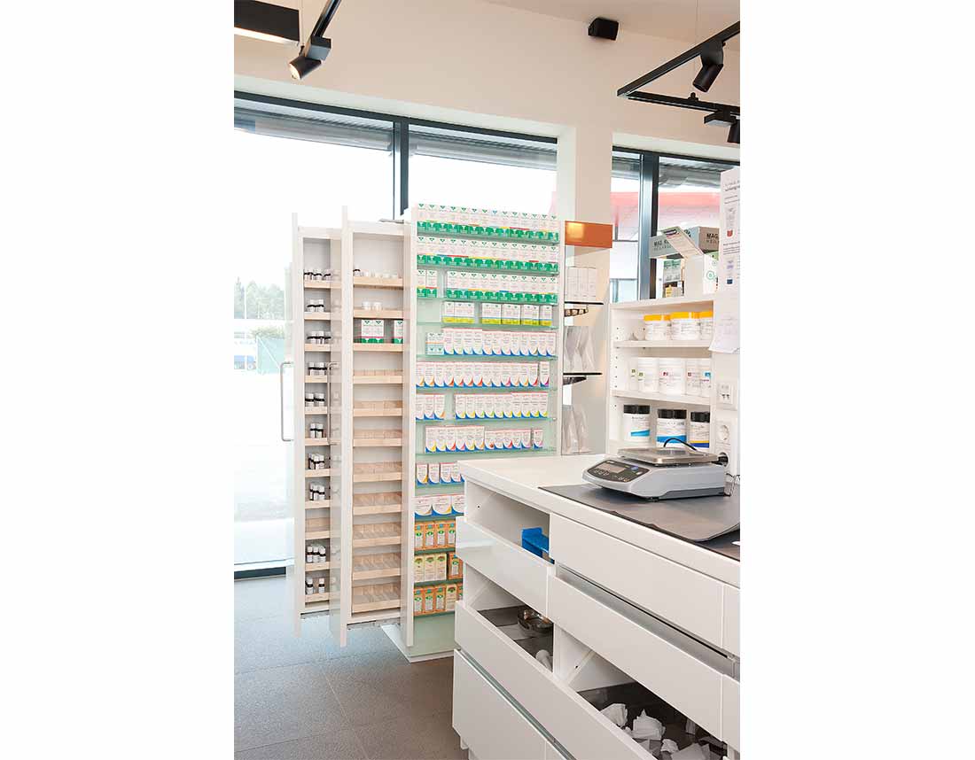 Schmale Medikamentenregale und Schubladensystem in einer Apotheke.