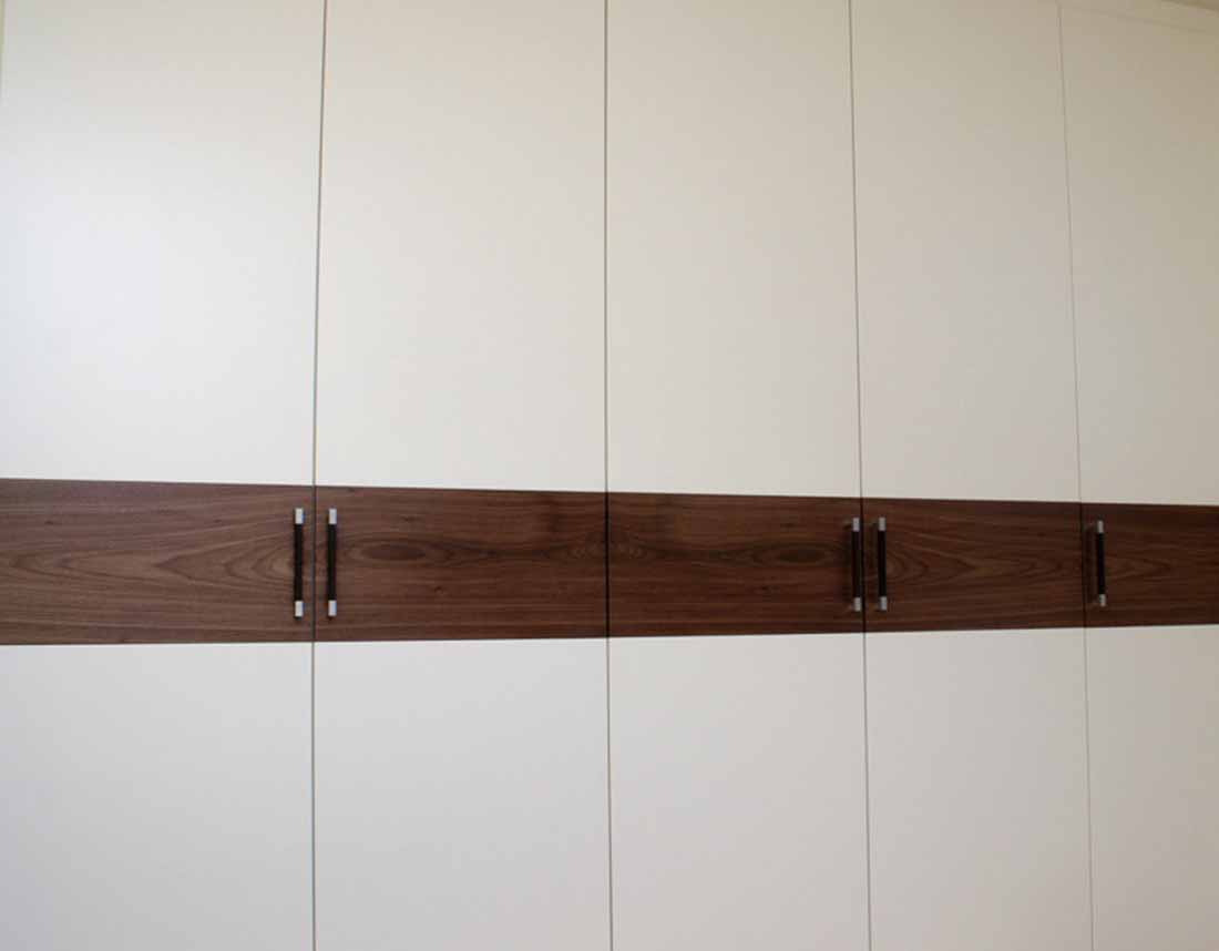 Hoher Kleiderschrank mit Holzstreifen und passenden Griffen.