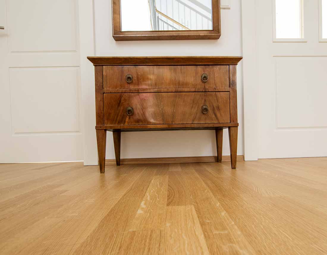 Holzboden mit antiker Kommode und Spiegel.