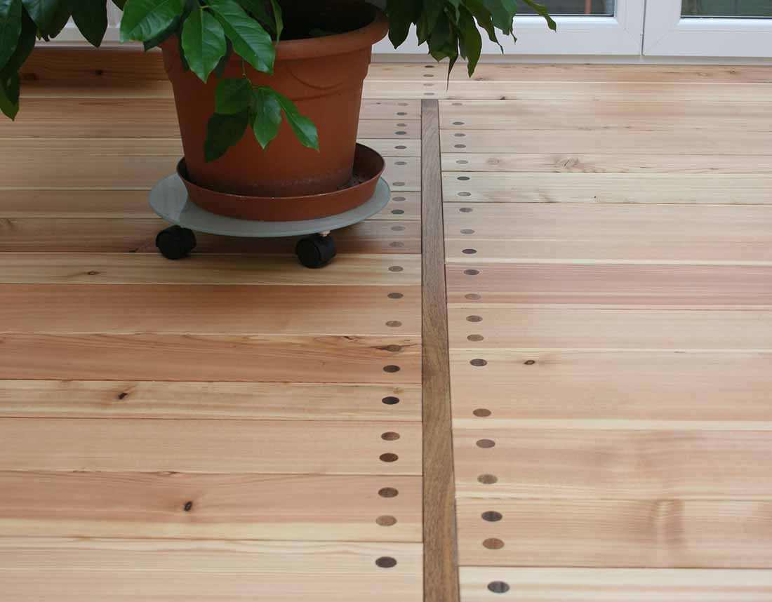 Holzboden mit Topfpflanze und markanten Befestigungen.