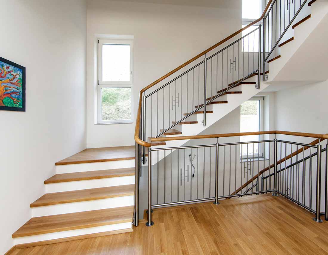 Holztreppe mit Metallgeländer und großen Fenstern.