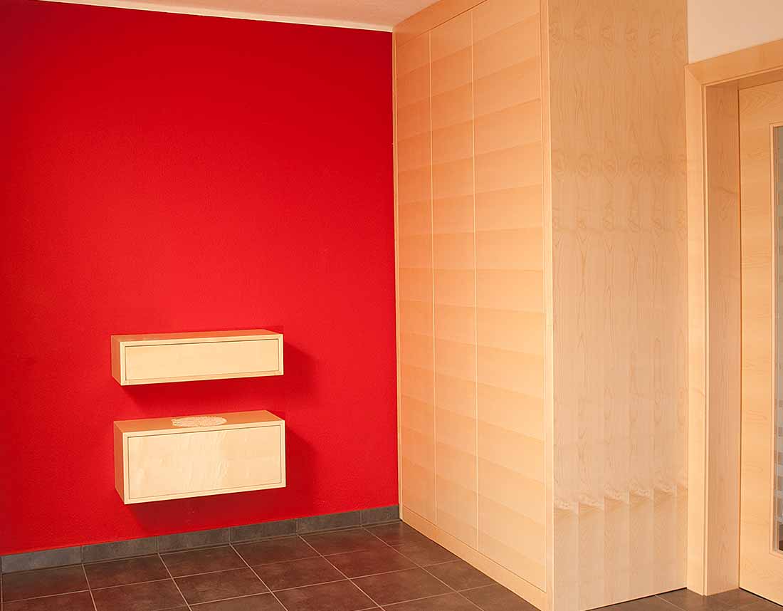 Modernes Vorzimmer mit roter Akzentwand und schwebenden Schränken.