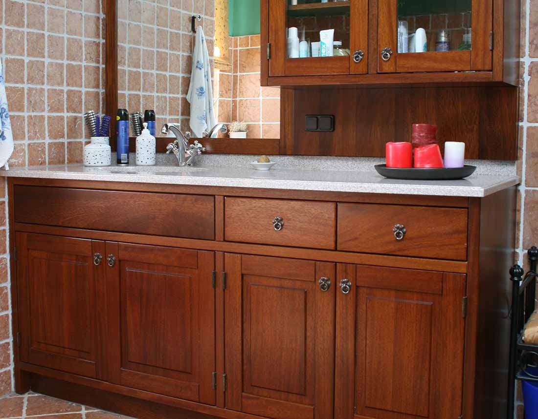 Badezimmer mit massiven Holzschränken und Spiegel, eingerichtet mit roten Kerzen.