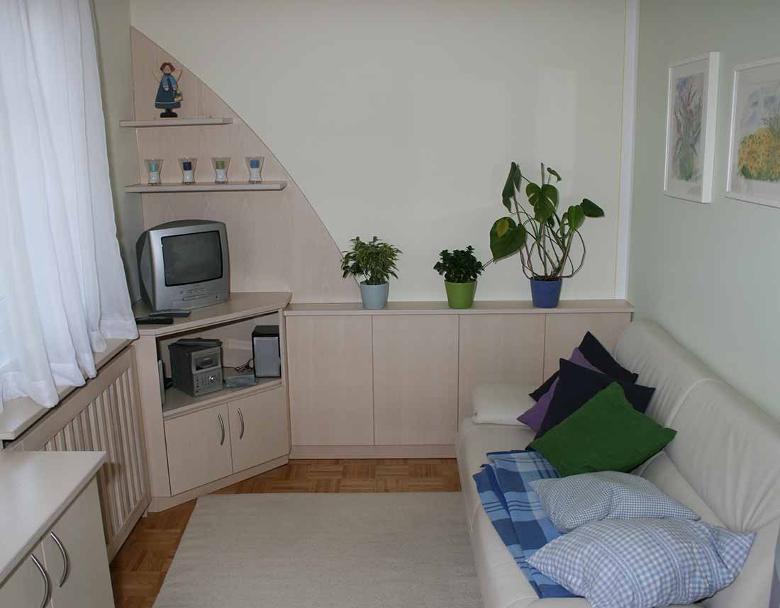 Wohnzimmer mit TV-Eckschrank und Sofa.