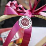 Ein Geschenkkorb mit einer pinken Schleife und einem BNI-Empfehlungssiegel „Ich empfehle BNI“.