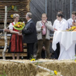 Eine Frau in Tracht erhält einen Blumenstrauß auf einer Bühne, umgeben von mehreren Personen.