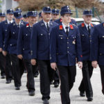 Gruppe von Feuerwehrmännern in blauen Uniformen marschiert in einer Reihe.