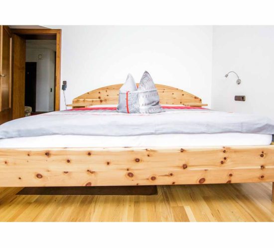 Breites Doppelbett aus Zirbenholz.
