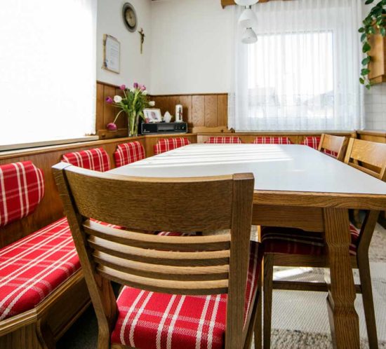 Traditioneller Essbereich mit Holztisch und rot karierten Sitzpolstern.