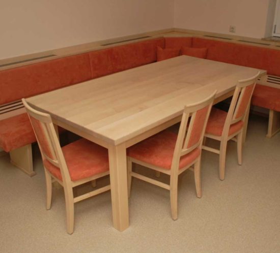 Essbereich mit hellem Holztisch, passender Eckbank und Stühlen, orange gepolstert.
