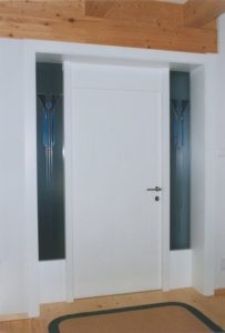 Weiße Tür mit dekorativen blauen Glaseinsätzen auf beiden Seiten.