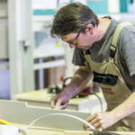 Handwerker arbeitet konzentriert an einem Holzstück in einer Werkstatt.