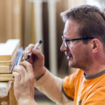 Handwerker zeichnet ein Holzstück ein