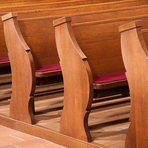 Seitliche Ansicht mehrerer Kirchenbänke mit geschnitzten Details.