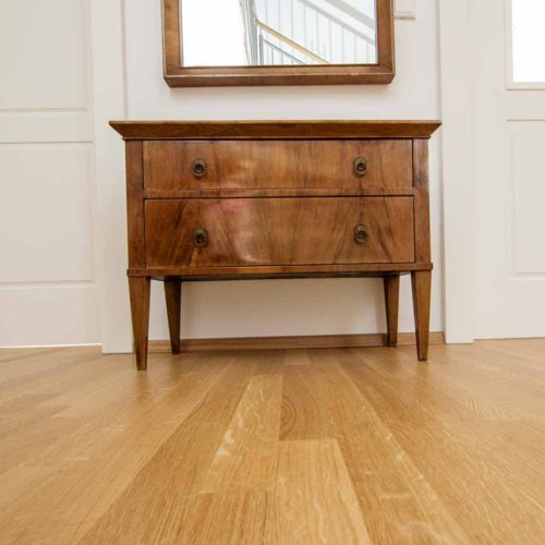 Holzboden mit antiker Kommode und Spiegel.
