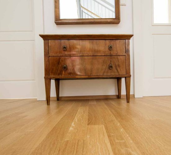 Holzboden mit antiker Kommode und Spiegel.