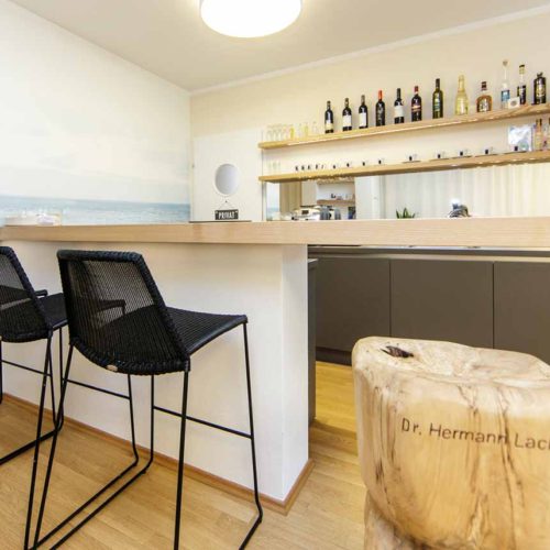 Moderne Bar mit Heller Holzplatte und schwarzen Stühlen