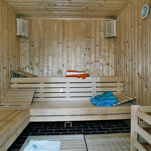 Innenansicht einer traditionellen Holzsauna mit Handtüchern auf den Bänken.