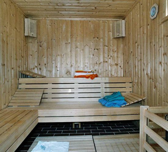 Innenansicht einer traditionellen Holzsauna mit Handtüchern auf den Bänken.