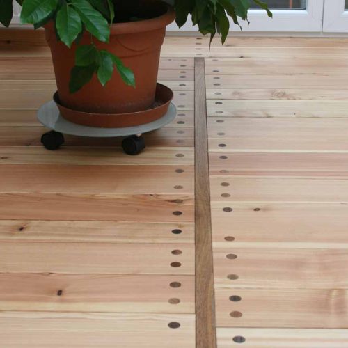Holzboden mit Topfpflanze und markanten Befestigungen.