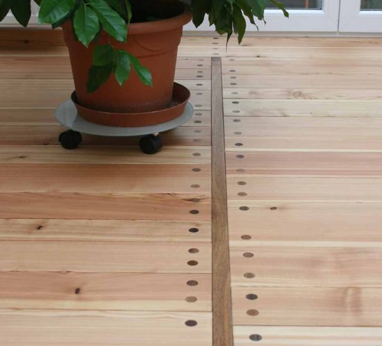 Holzboden mit Topfpflanze und markanten Befestigungen.