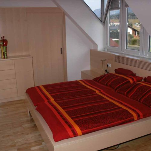Ahornholz-Schlafzimmer mit integriertem Schrank und Dachschräge.