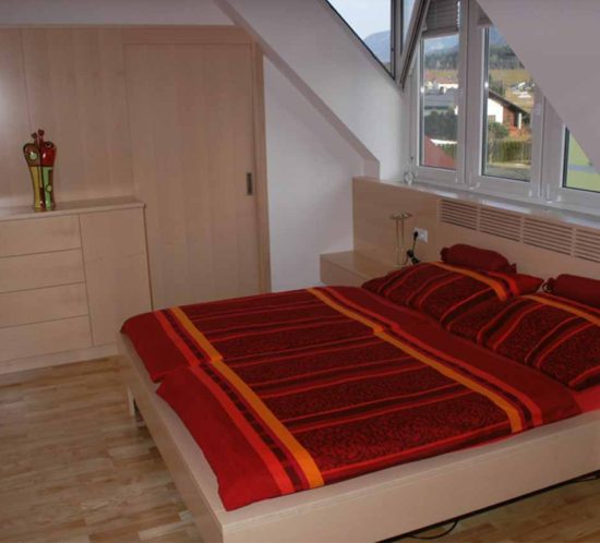Ahornholz-Schlafzimmer mit integriertem Schrank und Dachschräge.