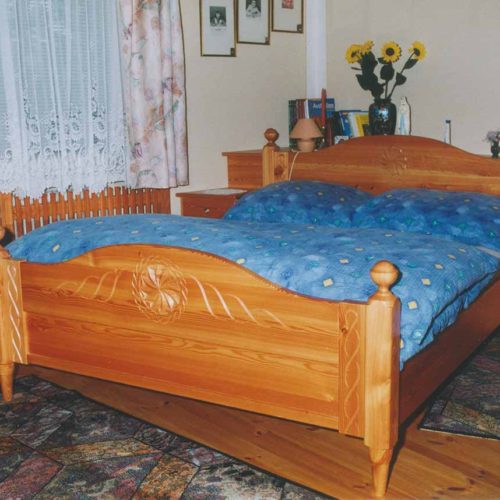 Klassisches Holz-Doppelbett mit geschnitztem Kopf- und Fußteil.