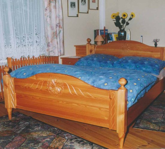 Klassisches Holz-Doppelbett mit geschnitztem Kopf- und Fußteil.