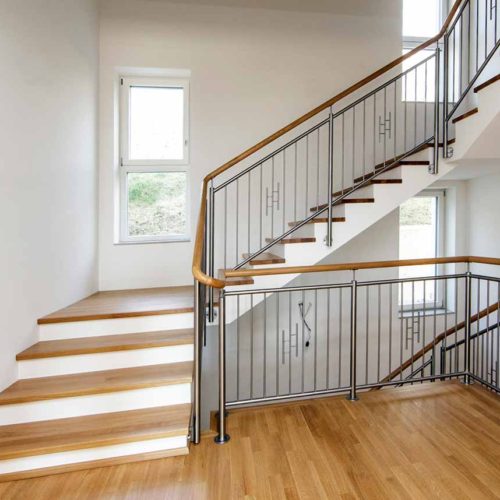 Holztreppe mit Metallgeländer und großen Fenstern.