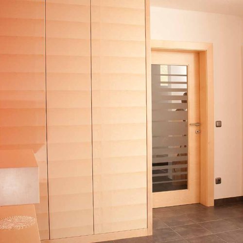 Ein heller Eingangsbereich mit modernen Holzschränken und roten Wänden.