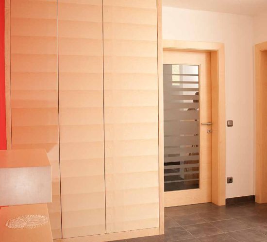Ein heller Eingangsbereich mit modernen Holzschränken und roten Wänden.