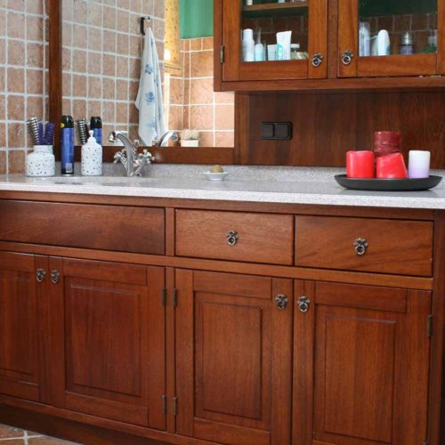 Badezimmer mit massiven Holzschränken und Spiegel, eingerichtet mit roten Kerzen.