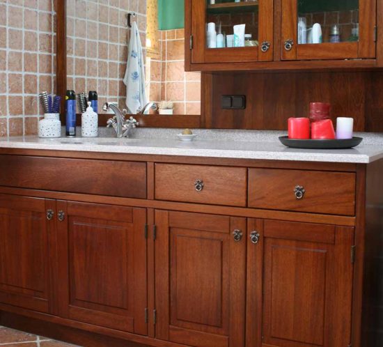 Badezimmer mit massiven Holzschränken und Spiegel, eingerichtet mit roten Kerzen.