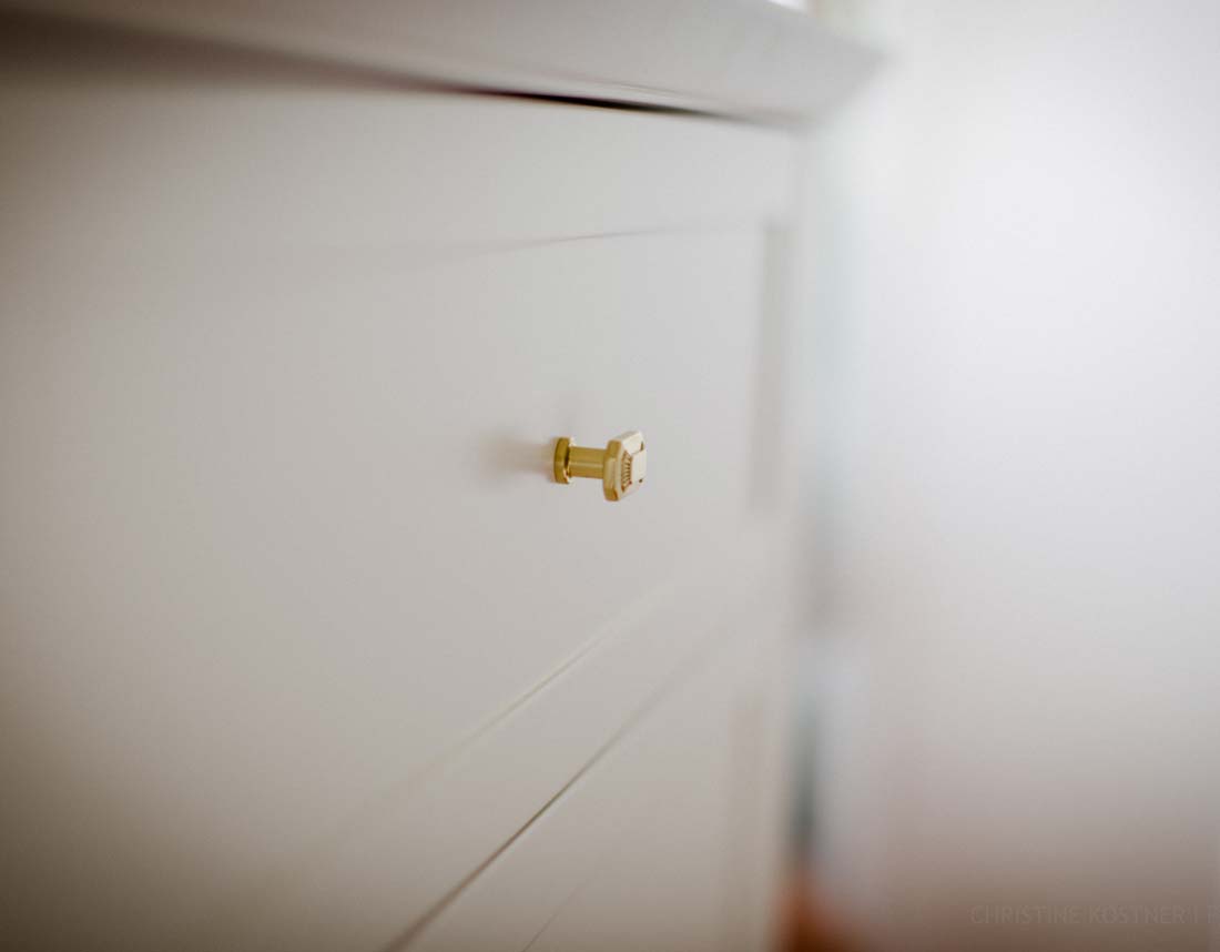 Nahaufnahme eines goldenen Schrankgriffs auf einer weißen Schrankoberfläche.