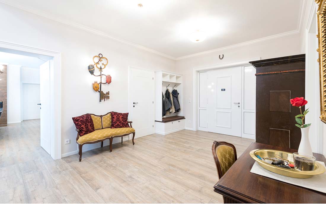 Heller Eingangsbereich mit antikem Sofa, moderner Garderobe und dekorativen Wandverzierungen.