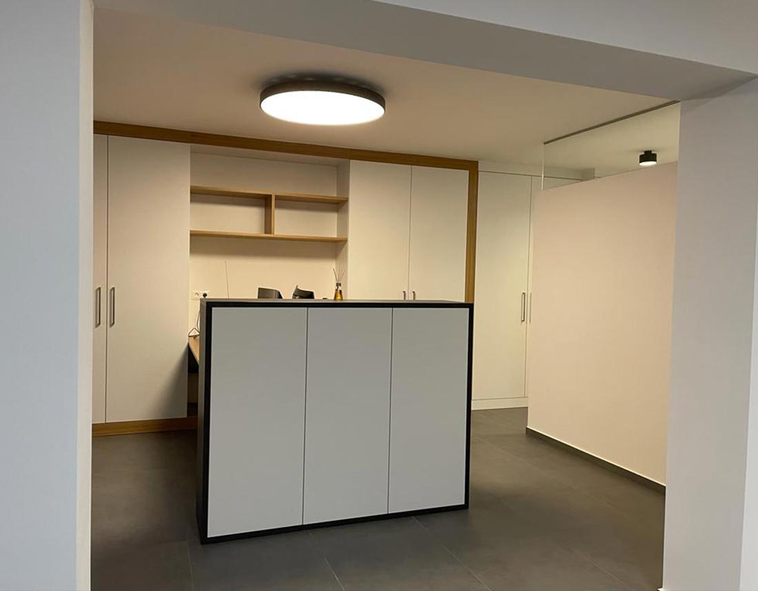 Modernes Büro mit weißem Empfangstresen und eingebauten Regalen.
