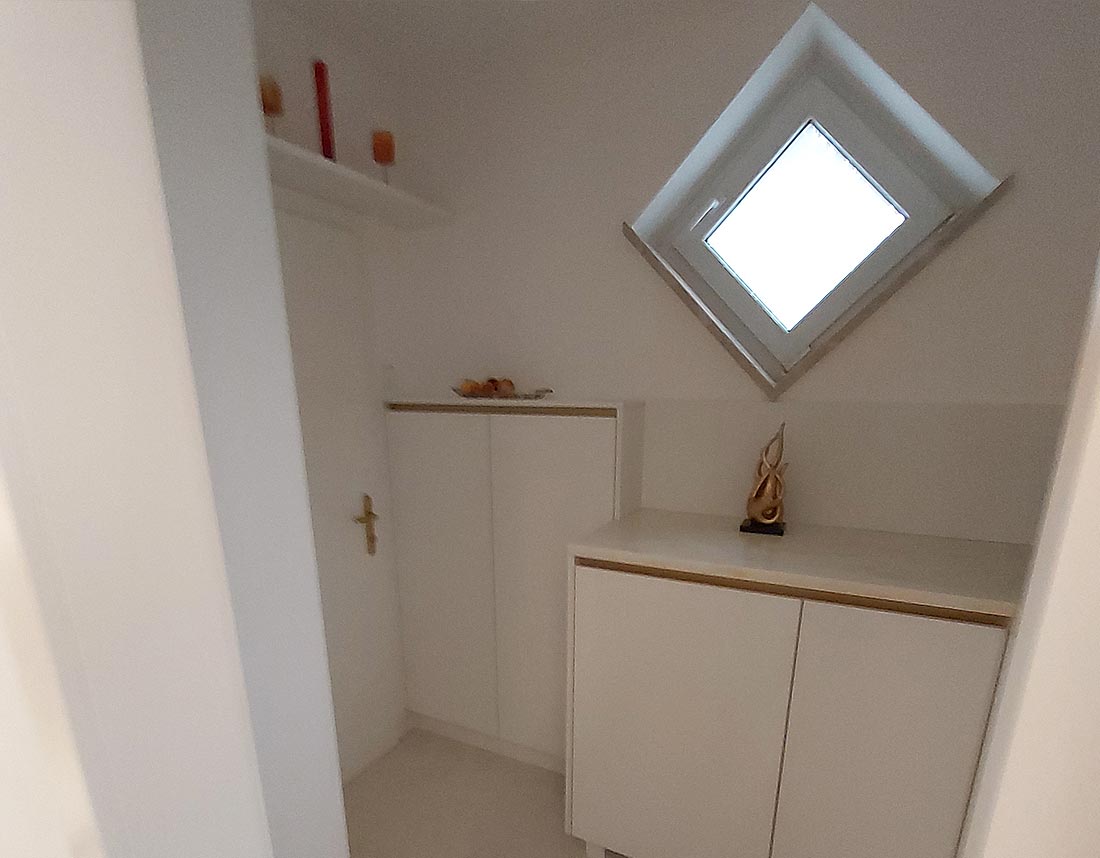 Kleiner Raum mit weißem Einbauschrank und schrägem Fenster