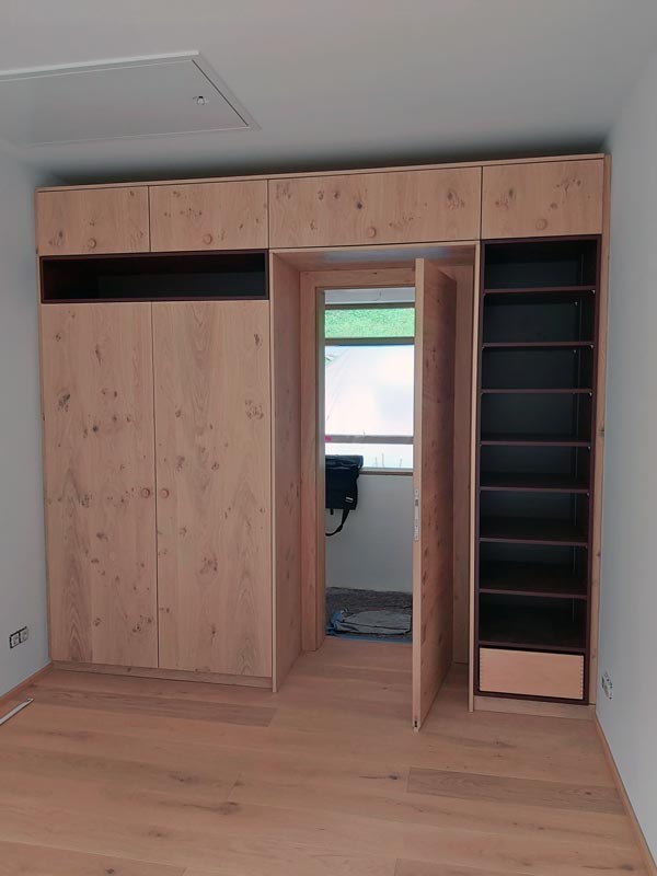 Einbauschrank mit geöffneter, versteckter Tür.