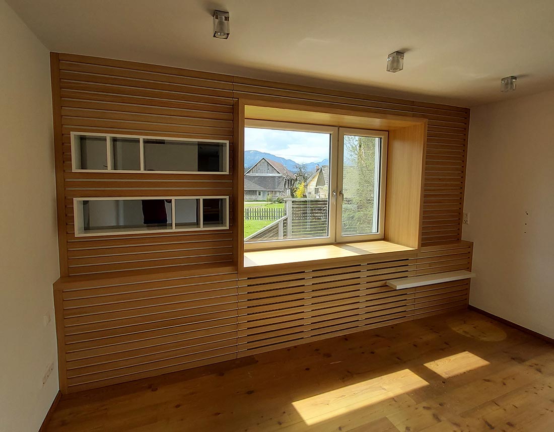 Maßgefertigte Wohnwand aus Lärchenholz mit integriertem Fenster und Regalen.