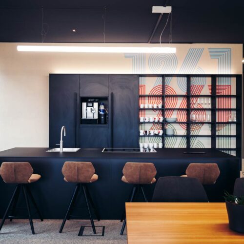 Moderne Büro-Kaffeeküche mit Barhockern und stilvoller Wandgestaltung