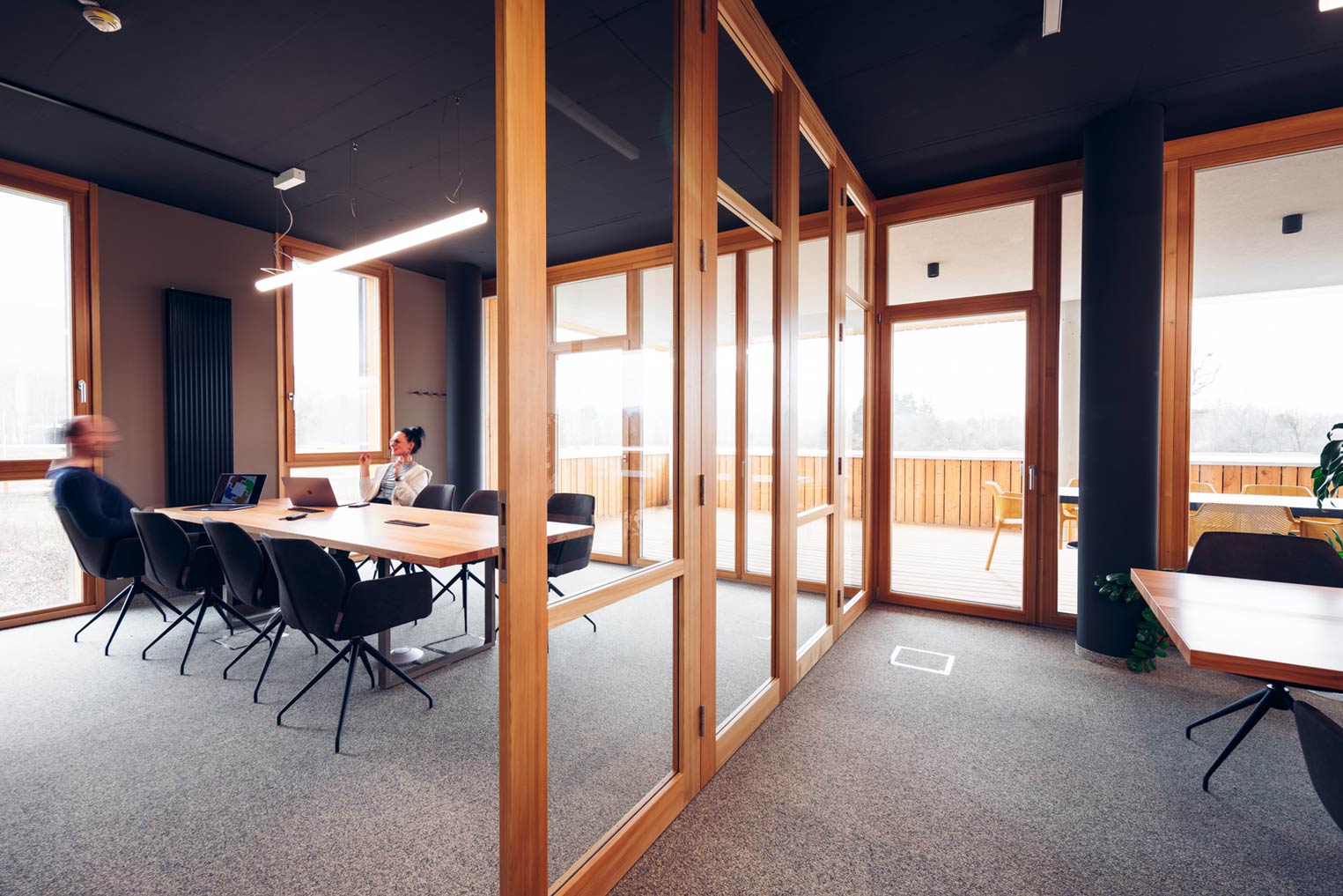 Ein modernes Büro mit Glaswänden und einer Besprechungsecke, in der zwei Personen arbeiten.