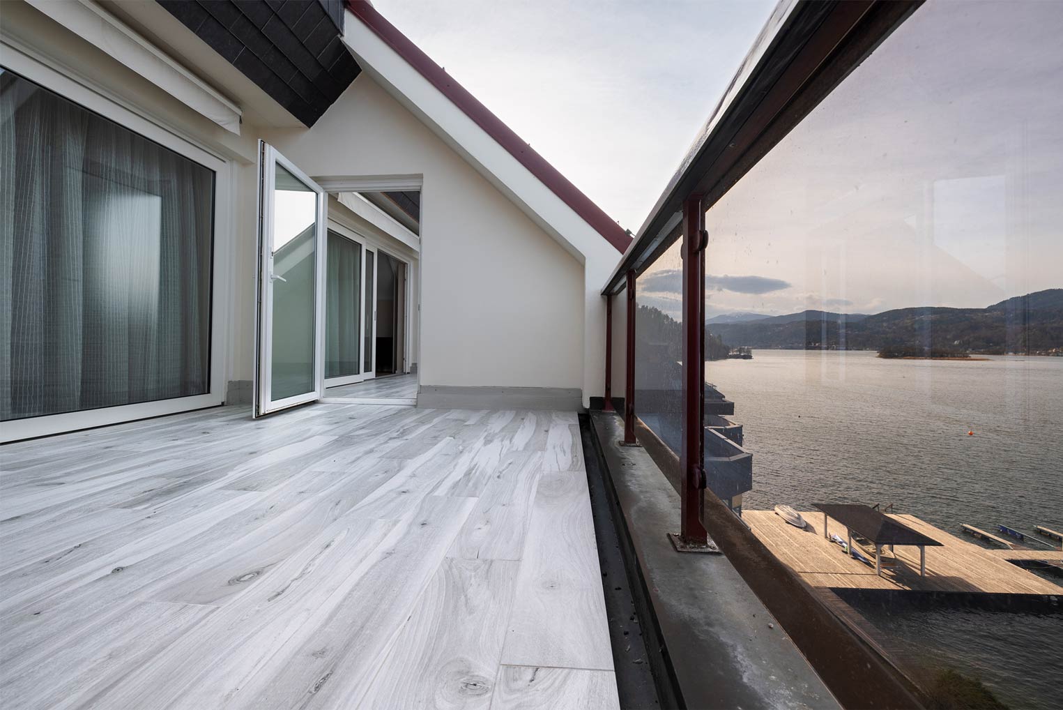 Terrasse mit Seeblick und Glasgeländer.