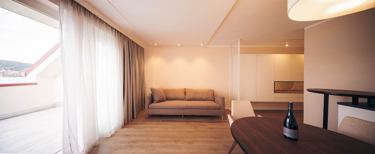 Modernes Wohnzimmer mit Sofa, Vorhängen und Zugang zum Balkon