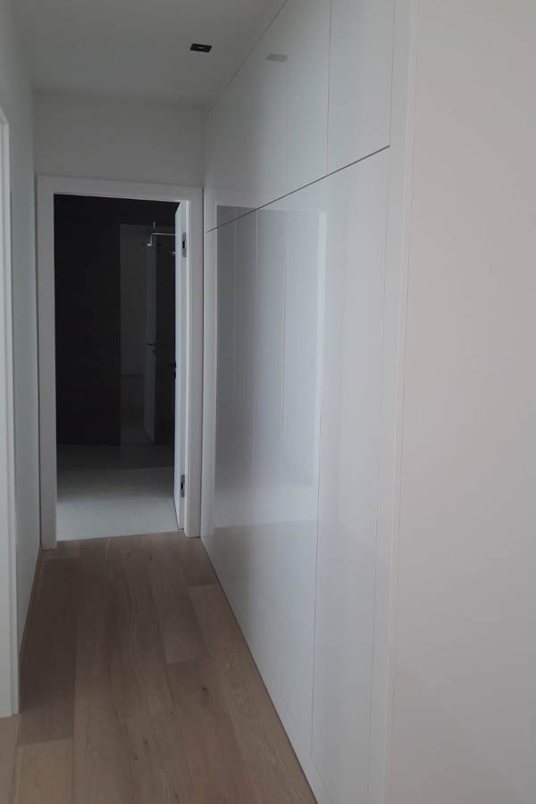 Weißer Flur mit Einbauschränken und Holzboden