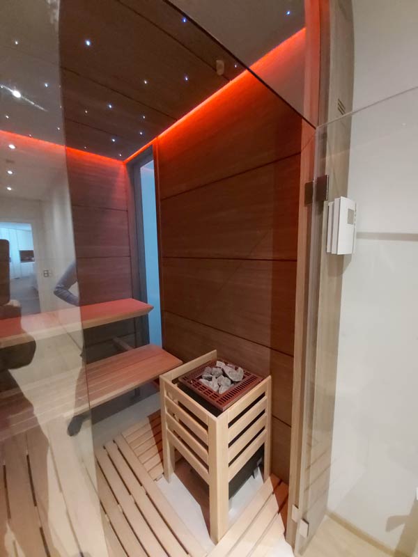 Moderne Sauna mit Holzverkleidung, Saunabank und roter LED-Beleuchtung