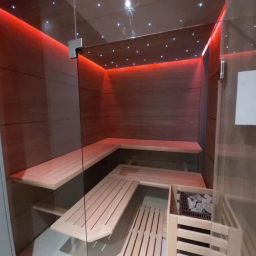 Moderne Sauna mit Eckbänken, Holzverkleidung und roter LED-Beleuchtung
