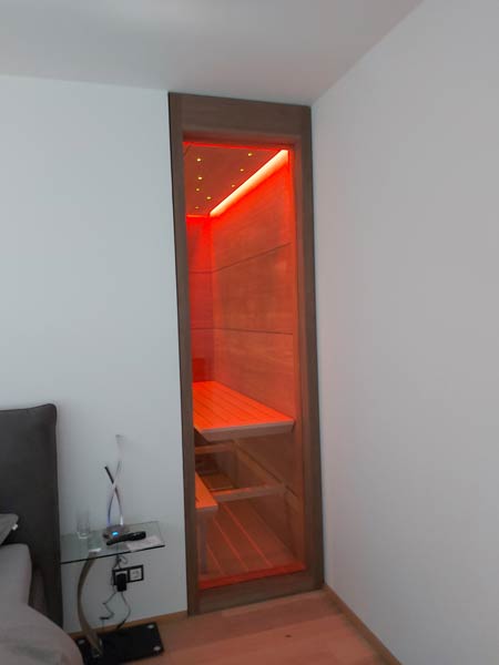 Eingebaute Sauna mit Glasfront und roter LED-Beleuchtung in einem Wohnraum