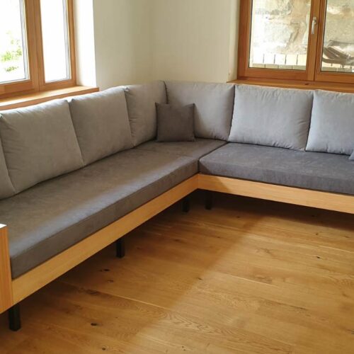 Ecksofa mit Holzrahmen und grauen Polstern in einem Wohnzimmer