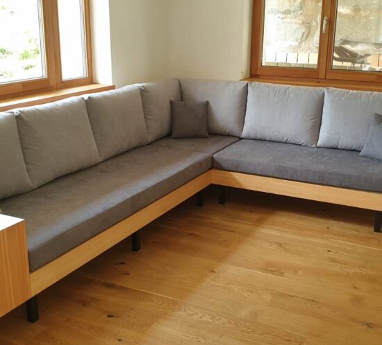 Ecksofa mit Holzrahmen und grauen Polstern in einem Wohnzimmer